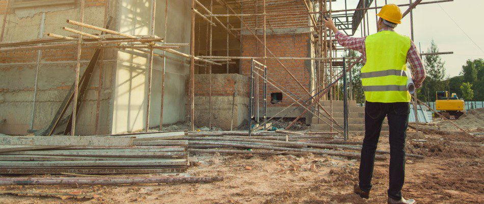 A construction worker is standing in front of a construction site.