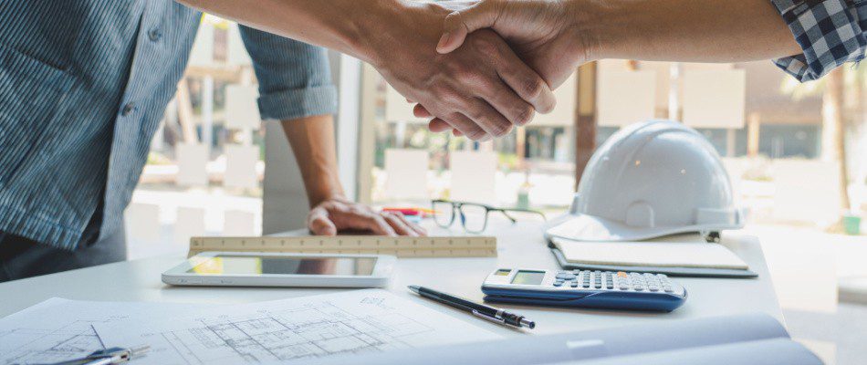 Two people shaking hands in front of a desk.