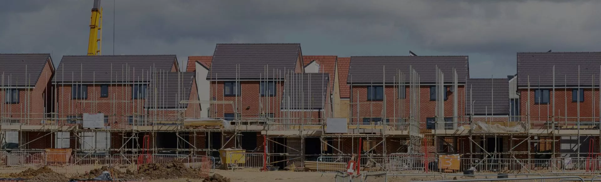 A row of houses under construction under a cloudy sky.